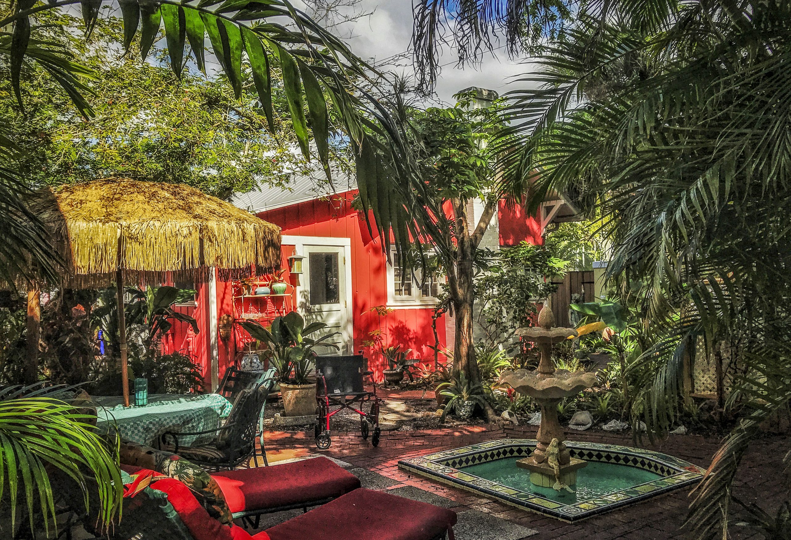Red Arsenault cottage surrounded by palms beside the courtyard fountain